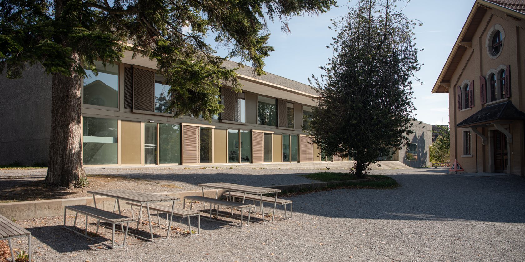 Schulhof mit Sitzbänken und Bäumen