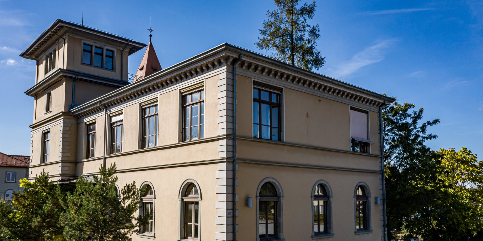 Schulgebäude und Bäume bei Sonnenschein